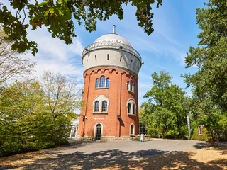 Camera Obscura, Mülheim an der Ruhr  Roter Backsteinturm der Camera Obscura in Mülheim, umgeben von grünen Bäumen unter blauem Himmel.