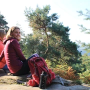 Ibbenbüren_Plisseefelsen_Stadtmarketing Ibbenbüren GmbH_SPL_2000.jpg Zwei Personen sitzen entspannt auf einem Felsen, umgeben von grünen Bäumen und genießen den Ausblick.