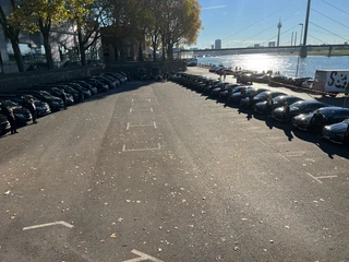 MTV EMA Awards 2022 Reihe parkender Autos an Uferpromenade mit Blick auf den Fluss und Fernsehturm im blauen Himmel.</p>Row of parked cars on the promenade with a view of the river and TV tower in the blue sky.</p> <p
