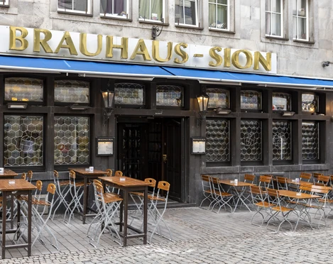 Brewery Sion Außengastronomie vor dem Brauhaus . An der Fassade steht in goldenen Buchstaben Brauhaus Sion.Outdoor dining in front of the Brauhaus . The words Brauhaus Sion are written on the façade in gold letters.