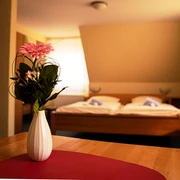 Havergoh Hotel_Doppelzimmer.jpg Zweibettzimmer mit Holzinterieur, Blumen in weißer Vase auf Tisch im Vordergrund, Tageslichtfenster.