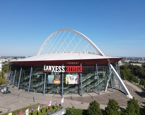 Eduard Bopp Fotografie Luftaufnahme der Lanxess Arena in Köln, ein markanter Veranstaltungsort mit futuristischem Design, großem Bogen und verglaster Fassade.Aerial view of the Lanxess Arena in Cologne, a striking venue with a futuristic design, large arch and glazed façade.