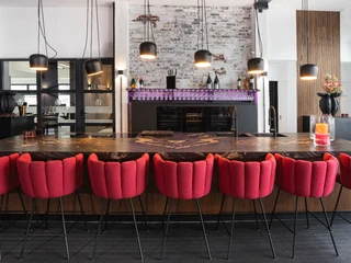 Interieur Moderner, heller Eventraum mit länglichen Tisch in der Mitte und roten StühleModern, bright event room with an elongated table in the middle and red chairs