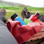 Lienen_Teutoschleife Holperdorper Picknick_Anja Schmidt.jpg Zwei Personen liegen auf einer Wiese, eine Picknickkiste mit Getränken und Decke zwischen ihnen.