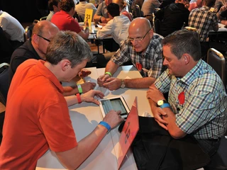 Interaktive Tagung Gruppenarbeit: Vier Männer sitzen an einem Gruppentisch um ein TabletGroup work: Four men sit at a group table around a tablet