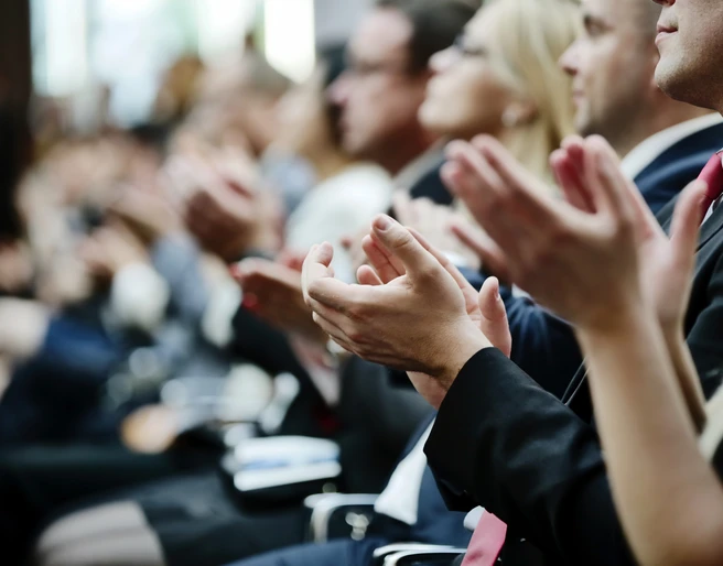 Tagung Klatschende Menschen mit schwarzer Kleidung sitzen in StuhlreihenClapping people with black clothing sit in rows of chairs