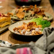 Tigermilch Das Bild zeigt einladende Teller mit kreativ angerichteten, frischen Gerichten und farbenfrohen Zutaten auf einem hölzernen Tisch bei warmem Licht.The image depicts inviting plates with creatively presented, fresh dishes featuring colorful ingredients, set on a wooden table under warm lighting.