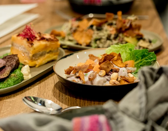 Tigermilch Das Bild zeigt einladende Teller mit kreativ angerichteten, frischen Gerichten und farbenfrohen Zutaten auf einem hölzernen Tisch bei warmem Licht.The image depicts inviting plates with creatively presented, fresh dishes featuring colorful ingredients, set on a wooden table under warm lighting.