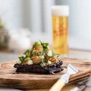 NeoBiota Ein kunstvoll angerichtetes Gourmetgericht mit frischen Kräutern und einem köstlichen Getränk im Hintergrund. An artfully arranged gourmet dish with fresh herbs and a delicious drink in the background.