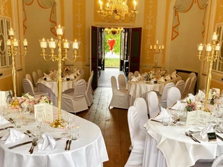 1524b72c-6fad-4b1a-ab45-27cfec470050.jpg Kleiner Raum im Barockstil mit weiß eingedeckten Banketttischen und opulenten KerzenständernSmall room in Baroque style with white-covered banquet tables and opulent candlesticks