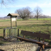 Stadt Rehburg-Loccum Kloster Asbeke Holzbank auf einer grünen Wiese nahe Rehburg-Loccum, umgeben von Bäumen und Feldlandschaft.