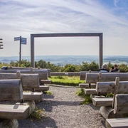 Landschaftskino Köterberg Freiluftkino auf dem Köterberg, Holzbänke mit Aussicht auf weite Hügel und geführte Wanderwege.