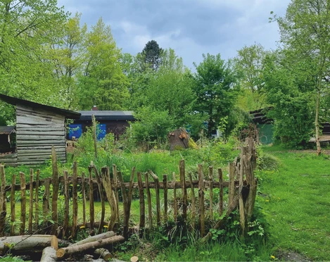 Abenteuerspielplatz Buntspecht  Mehrere Holzhütten auf dem Außengelände des Abenteuerspielplatzes Buntspecht, umgeben von Bäumen und Spielflächen