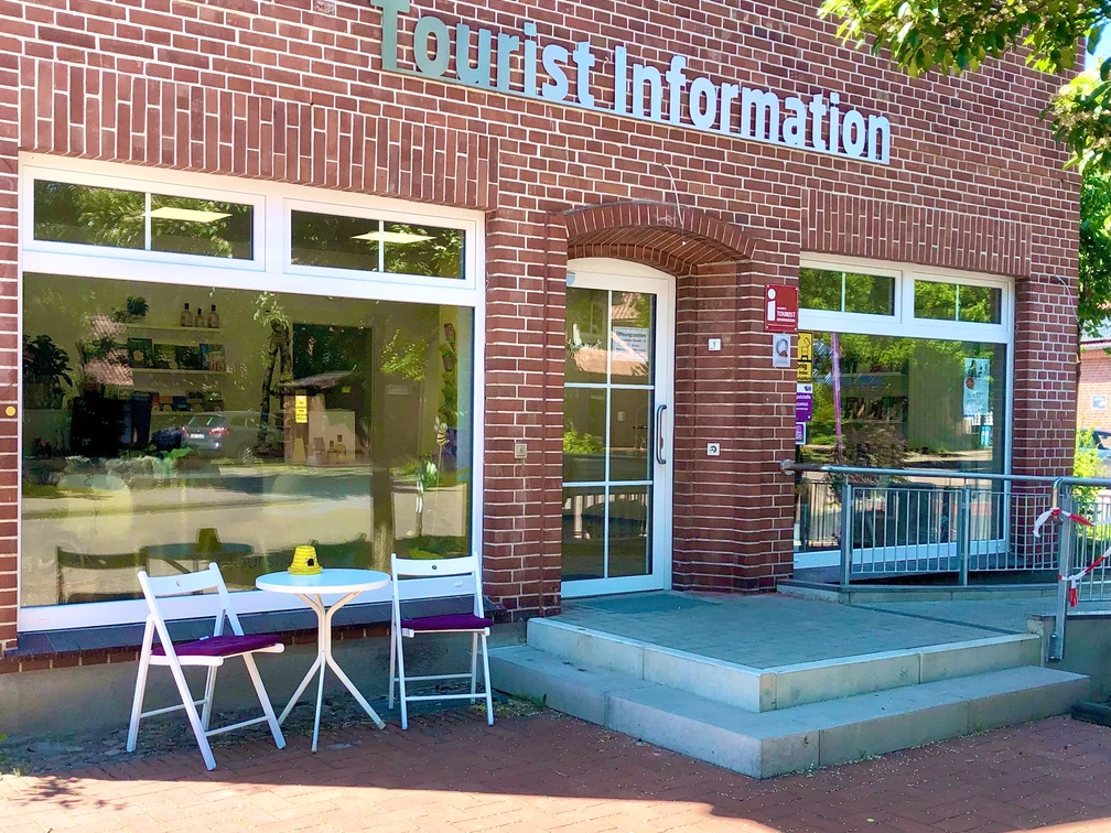 Tourist-Information Ein rotes Backsteingebäude mit der Aufschrift "Tourist Information". Ein Tisch und zwei Stühle stehen vor dem Eingang.A red brick building with the inscription "Tourist Information". A table and two chairs stand in front of the entrance.