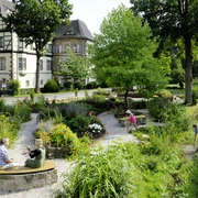 Schulklostergarten Neuenheerse Menschen genießen den gepflegten Schulklostergarten Neuenheerse, umgeben von historischen Gebäuden.