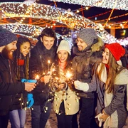 Happy friends with sparklers at a fair at christmas Teamfoto auf dem Weihnachtsmarkt: Personen halten Wunderkerzen in den HändenTeam photo at the Christmas market: people holding sparklers in their hands