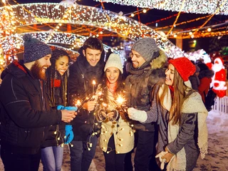 Happy friends with sparklers at a fair at christmas Teamfoto auf dem Weihnachtsmarkt: Personen halten Wunderkerzen in den HändenTeam photo at the Christmas market: people holding sparklers in their hands