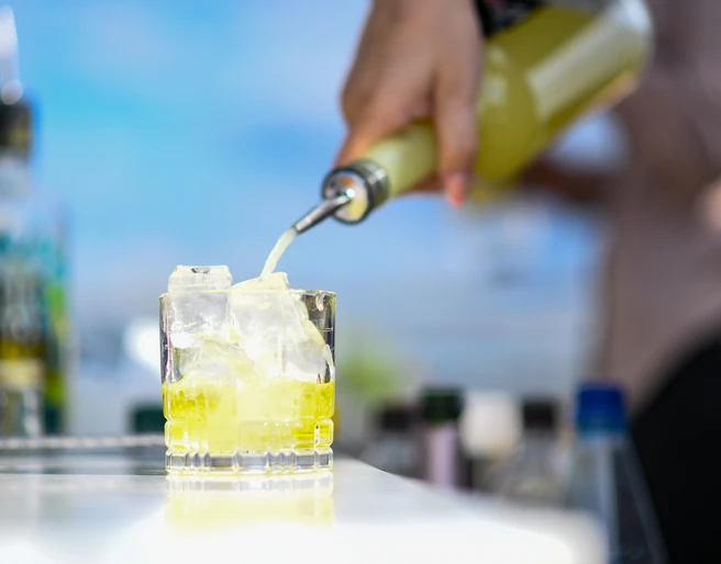 ESG_SummerStart2021_SZW_165.jpg Knallgelber Cocktail wird aus einer Flasche in ein Glas gegossenBright yellow cocktail is poured from a bottle into a glass