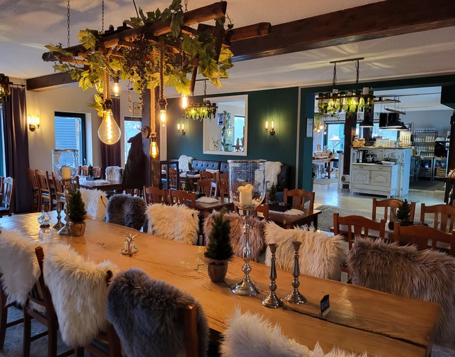 Kruegers_Gastraum_innen_01.jpg Ein rustikal eingerichteter Gastraum mit Holztischen, gemütlichen Stühlen und dekorativen Pelzkissen.