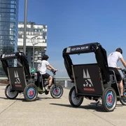 Rikolonia Citytour Rheinauhafen Zwei Rikschafahrer stehen in Rheinauhafen KölnTwo rickshaw drivers stand in Cologne's Rheinauhafen