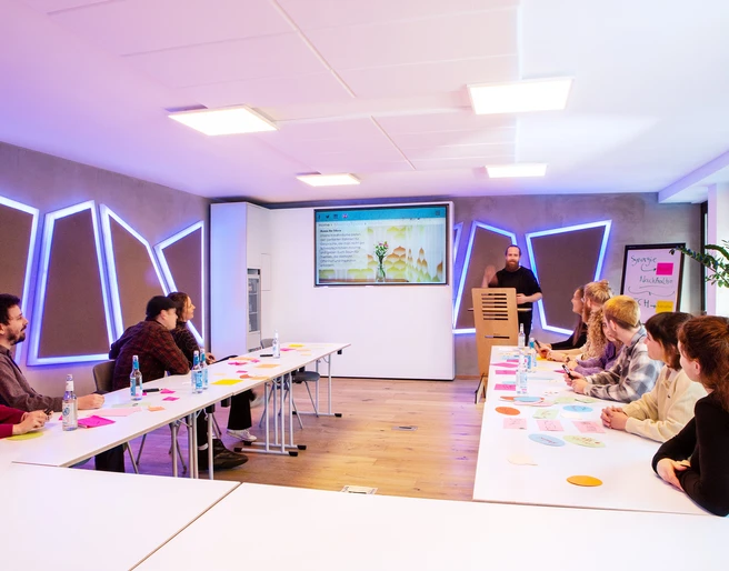 The Pattern Beuys 1.jpg Stylischer Konferenzraum mit Menschen, die in U-Form sitzenStylish conference room with people sitting in a U-shape