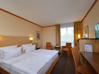 Hotelzimmer im Sure Hotel by Best Western Hilden-Düsseldorf Helles Hotelzimmer mit einem großen Doppelbett, zwei Stühlen, einem Tisch und einem Schreibtisch mit Fernseher.