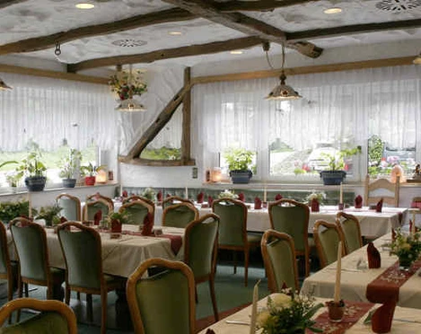 Gastraum im Hotel und Restaurant Haaner Hof in Haan Gemütlicher Gastraum mit rustikalem Holzgebälk, gedeckten Tischen und großen Fenstern mit Blumenschmuck.