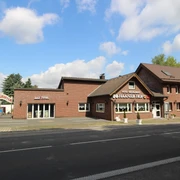 Hotel und Restaurant Haaner Hof Das Bild zeigt ein Backsteingebäude mit Restaurant Haaner Hof, umgeben von Bäumen und blauen Himmel.