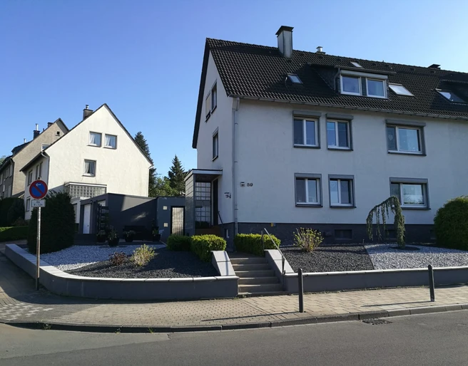 Ferienwohnung Das Fischerhaus in Velbert Dreigeschossiges Wohngebäude mit weißer Fassade und Schieferdach in einer ruhigen Wohngegend.