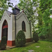 Bredemeiers Kapelle in Hövelhof, umgeben von Bäumen, mit spitzem Dach und dekorativen Fenstern.