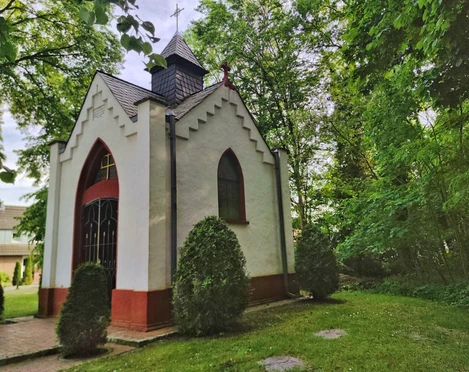 Bredemeiers Kapelle in Hövelhof, umgeben von Bäumen, mit spitzem Dach und dekorativen Fenstern.