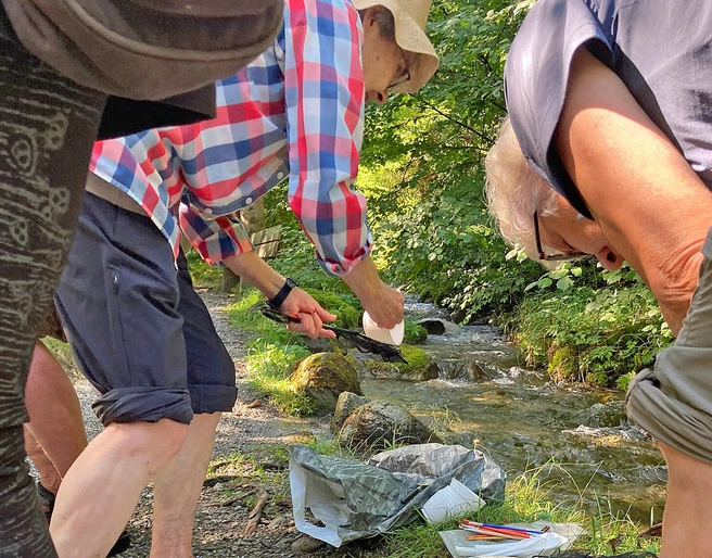 Forschen an der Quelle Exkursionsteilnehmende bücken sich über eine Quelle und untersuchen das WasserExcursion participants bend over a spring and examine the waterLes participants à l'excursion se penchent au-dessus d'une source et examinent l'eau.