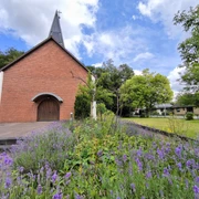 Evangelische Johanneskirche Hövelhof aus rotem Ziegel mit einem Stufengiebel und modernem Anbau.