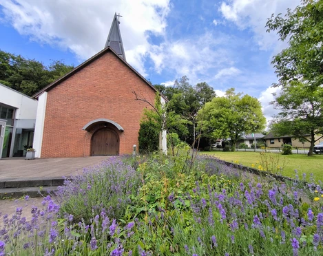 Evangelische Johanneskirche Hövelhof aus rotem Ziegel mit einem Stufengiebel und modernem Anbau.