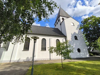 Herz-Jesu-Kirche Hövelriege Die Herz-Jesu-Kirche in Hövelriege, weiß getüncht, mit Glockenturm und umliegenden Grünflächen.