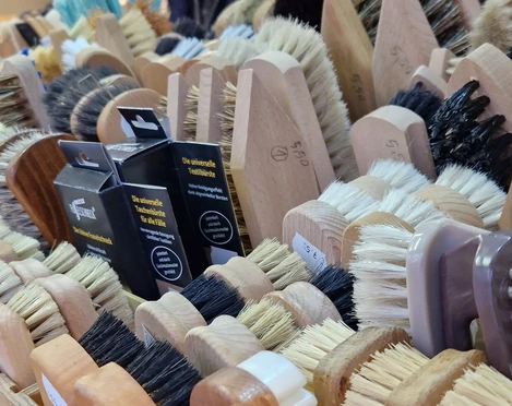 Eine Nahaufnahme handgefertigter Bürsten in verschiedenen Formen und Farben auf einem Marktstand.