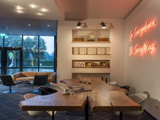 Lobby im Four Points Flex by Sheraton Ratingen Düsseldorf Airport Lobby mit modernem Holztisch, gemütlichen Sitzbereichen und stimmungsvoller Beleuchtung in Ratingen.