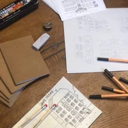 Cromforder Scribble Book Skizzen und Zeichenmaterial am Holztisch; Fokus auf architektonische Darstellungen historischer Gebäude.