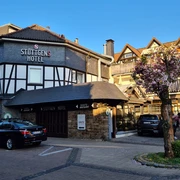 Außenansicht des Stüttgens Hotels in Velbert Fachwerk-Hotelgebäude in Velbert. Autos parken vor dem Eingang, daneben ein blühender Kirschbaum.