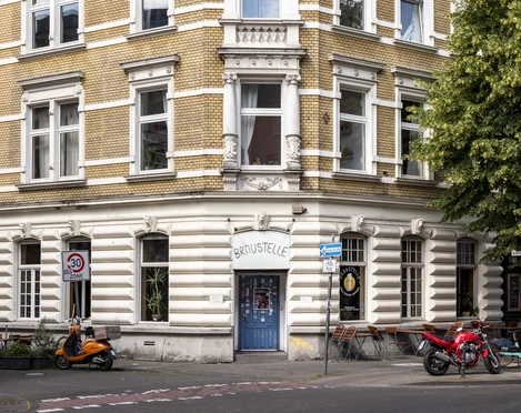 Braustelle Historisches Eckgebäude mit gelben Backsteinen, dekorativem Giebel, Schild mit „Braustelle“. Historic corner building with yellow bricks, decorative gable, sign with "Braustelle".