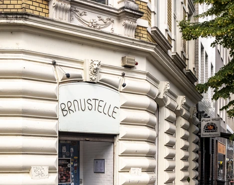 Braustelle Historische Fassade mit gelben Backsteinen. Der Eingang zur Braustelle führt durch eine blaue Tür.