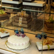 Cafe Reichard Vitrine mit schön verzierten Präsenten und üppiger Torte mit Marzipandekor. Display case with beautifully decorated presents and a lavish cake with marzipan decoration.