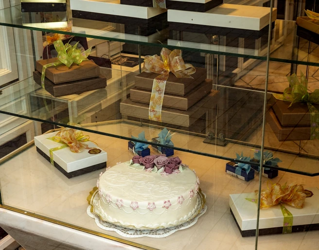 Cafe Reichard Vitrine mit schön verzierten Präsenten und üppiger Torte mit Marzipandekor. Display case with beautifully decorated presents and a lavish cake with marzipan decoration.