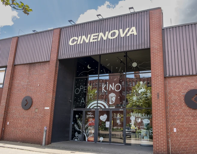 Cinenova Das Kino Cinenova befindet sich in einem roten Backsteingebäude mit einer modernen Glasfront, verziert mit kunstvollen Illustrationen. The Cinenova cinema is located in a red brick building with a modern glass facade adorned with artistic illustrations.