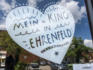 Cinenova Herzförmiger Aufkleber auf einer Glasfront mit der Aufschrift 'Mein Kino in Ehrenfeld' in lebhaften Schriftarten und Grafiken.Heart-shaped sticker on a glass front with the inscription 'Mein Kino in Ehrenfeld' in vivid fonts and graphics.