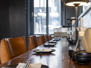 Daikan Izakaya Bar Eingedeckte Theke mit dunklen Tellern und Essstäbchen.Set counter with dark plates and chopsticks.