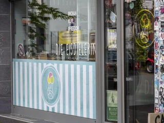 Die Eisdielerin Glasfront vom Eiscafe mit urbanem Flair durch bunte Sticker an der Hauswand.Ice cream parlor with urban flair thanks to colorful stickers on the glass front.