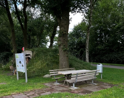 Rastplatz an der Plaggenhütte.jpg Ein ruhiger Rastplatz mit Holzbank und Tisch auf einem gepflegten Rasen, umgeben von Bäumen.