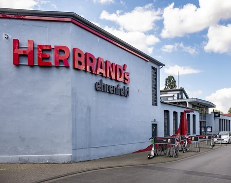 Herbrand's Hausfassade mit der Aufschrift Herbrands in großen roten Buchstaben.House front with the inscription Herbrands in large red letters.