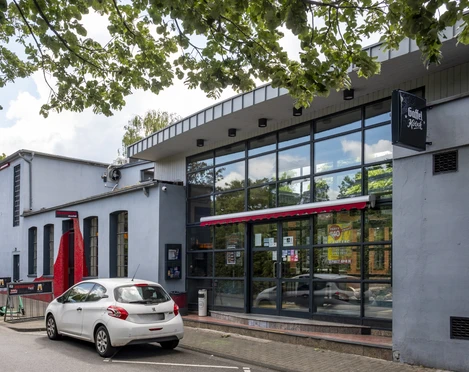 Herbrand's Außenansicht auf das Herbrands mit großer Glasfront und Fahrradständer davor.Exterior view of the Herbrands with large glass front and bicycle racks in front of it.